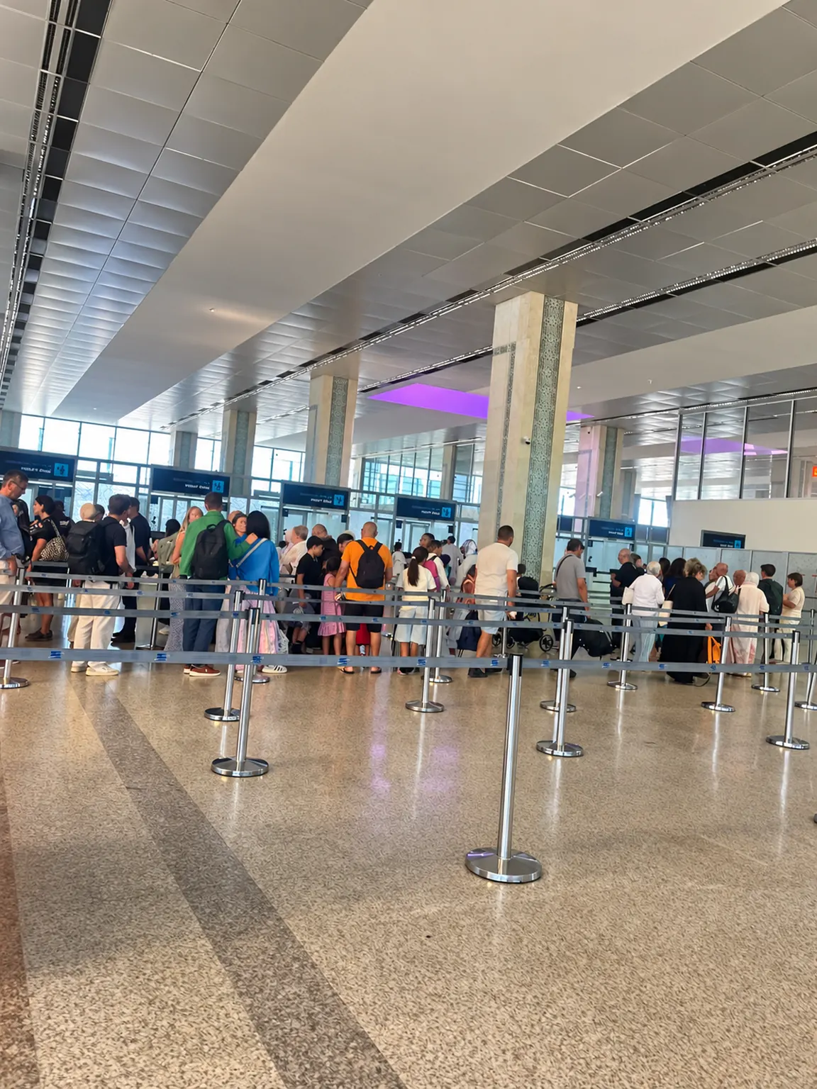 Voyageurs dans une file d’attente délimitée par des barrières à l’aéroport