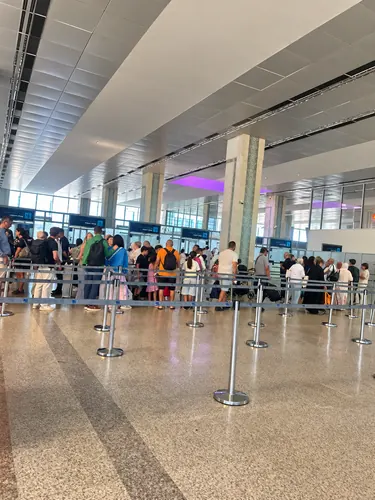 Voyageurs dans une file d’attente délimitée par des barrières à l’aéroport