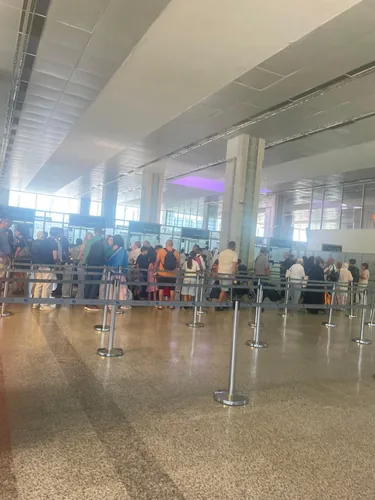 Voyageurs dans une file d’attente délimitée par des barrières à l’aéroport